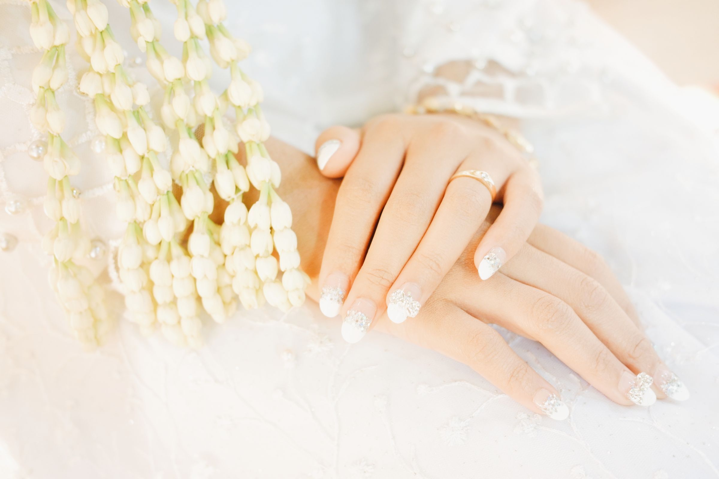 A bride’s hands with a milky pearl French resting on lace